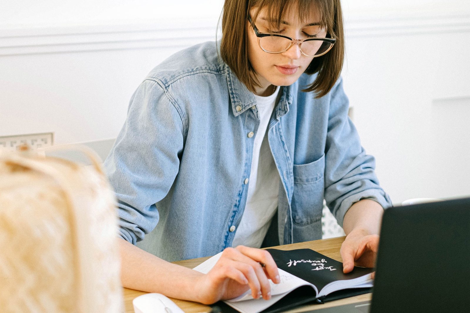 Writer reviewing notes beside a laptop in a bright home office.